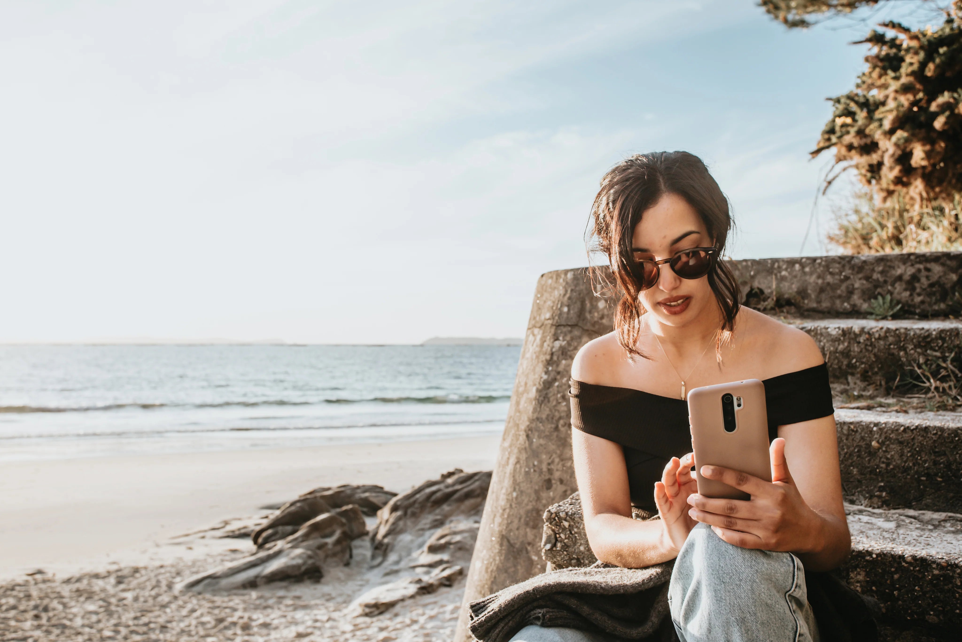 files/person-sits-on-steps-by-a-beach-looking-at-their-phone.webp